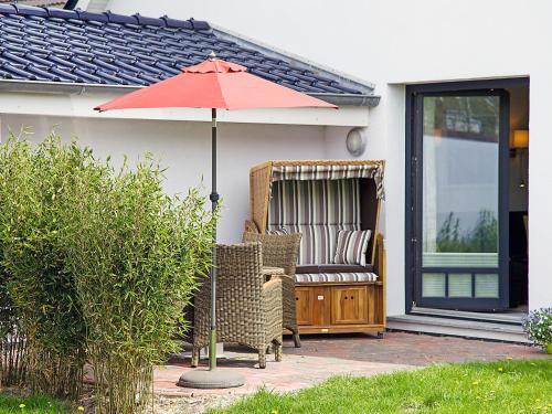 - un parasol rouge et des chaises sur la terrasse dans l'établissement Apartment Witthuus-Baltrum by Interhome, à Norddeich