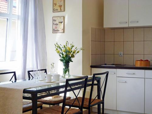 a kitchen with a table with a vase of flowers on it at Holiday Home Domek Joanna-2 by Interhome in Łeba