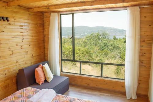 um quarto com uma grande janela numa casa de madeira em Luna Llena Cabañas em Guatavita