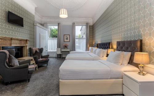 um quarto de hotel com duas camas e uma lareira em Clifden House by Nina em Dublin