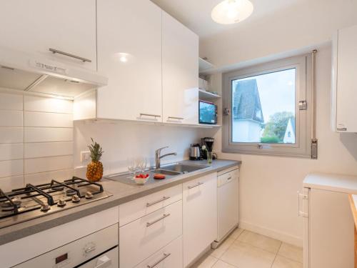 une cuisine avec des armoires blanches, un évier et une fenêtre dans l'établissement Apartment La Sauvagère-1 by Interhome, à Carnac-Plage