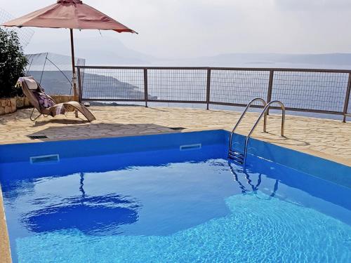 a blue swimming pool with an umbrella on a balcony at Holiday Home Puntiti 3 by Interhome in Kókkinon Khoríon