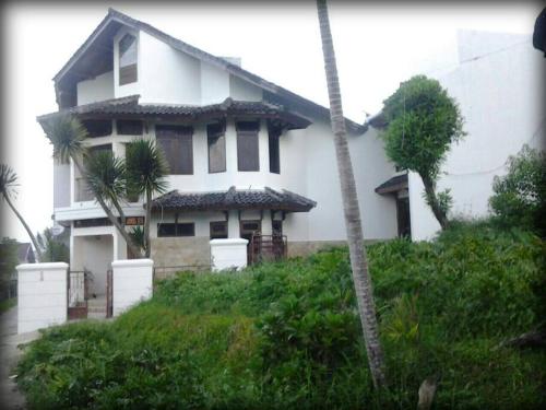 een wit huis met palmbomen ervoor bij Notes From The Mountains in Bandung