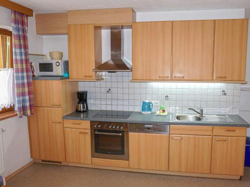 cocina con armarios de madera, fregadero y microondas en Apartment Stark by Interhome en Pettneu am Arlberg