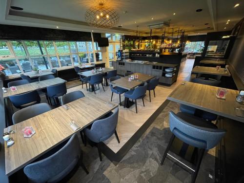 un restaurante con mesas de madera y sillas azules en Hotel Middelburg, en Middelburg