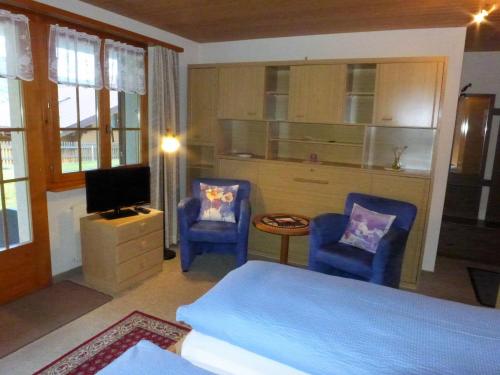 um quarto com duas cadeiras azuis e uma cama e uma televisão em Apartment Lohnerhus-2 by Interhome em Grindelwald