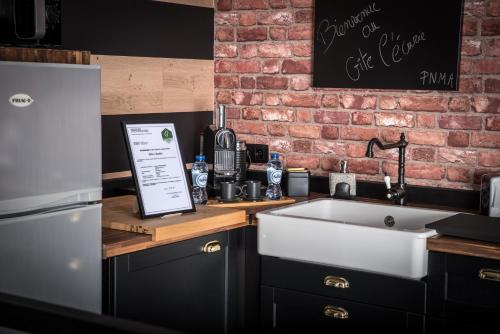 a kitchen with a white sink and a brick wall at L'écurie gîte duplex Welness in Spa