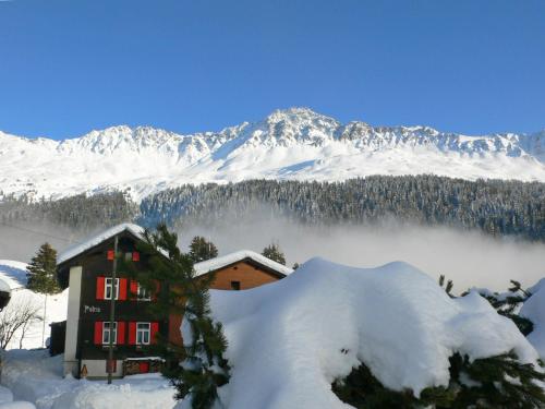 a house in the snow with mountains in the background at Apartment Chesa Boffalora by Interhome in Valbella