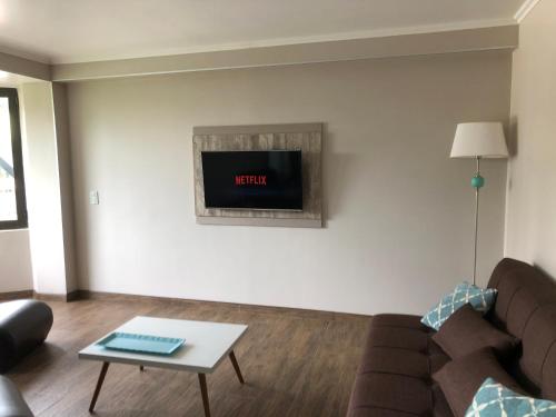 a living room with a couch and a tv on the wall at Perito Moreno - 3ro A in Puerto Iguazú