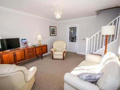 a living room with white furniture and a flat screen tv at Holiday Home Devonvale Place by Interhome in Kinross