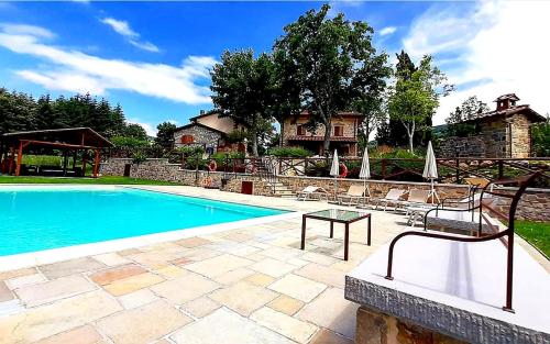 a swimming pool with chairs and a house in the background at L'Antico Cipresso in Poppi