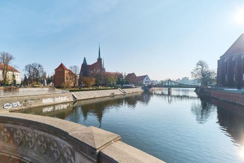 een rivier in een stad met een brug en gebouwen bij Studio Wyspa Słodowa by Renters in Wrocław