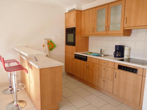 een kleine keuken met houten kasten en een rode kruk bij Apartment Ardévine 5 by Interhome in Ovronnaz