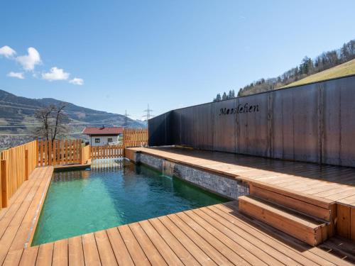 a pool with a wooden deck and a swimming poolvisor at Apartment Mooslehen-2 by Interhome in Schattberg