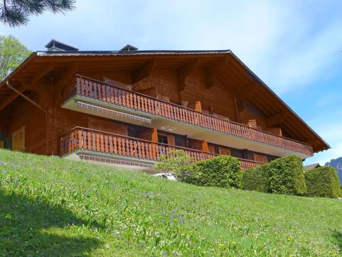 a building on top of a hill with a green field at Apartment Les Aiguilles d'Argent 10 by Interhome in Chesières