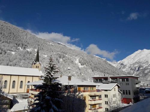 a town with a church and a snow covered mountain at Apartment Im Stahle by Interhome in Fiesch