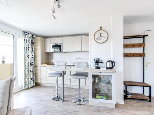 une cuisine avec des armoires blanches et un comptoir avec des tabourets dans l'établissement Apartment Port Guillaume-15 by Interhome, à Cabourg