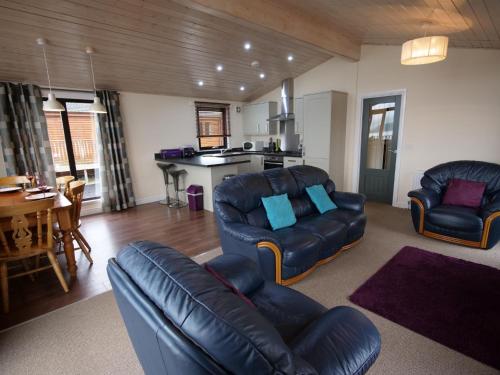 een woonkamer met een bank en stoelen en een keuken bij Chalet Loch Leven Lodge by Interhome in Ballingry