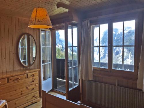 een badkamer met ramen, een spiegel en een wastafel bij Apartment Plein Soleil by Interhome in Wengen