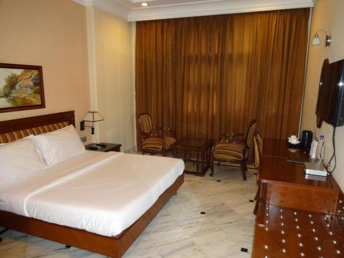 Dormitorio con cama, escritorio y TV en Florence Inn, en Nueva Delhi