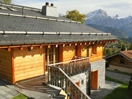 a wooden house with a balcony and mountains in the background at Chalet Chalet Maurice by Interhome in Chesières