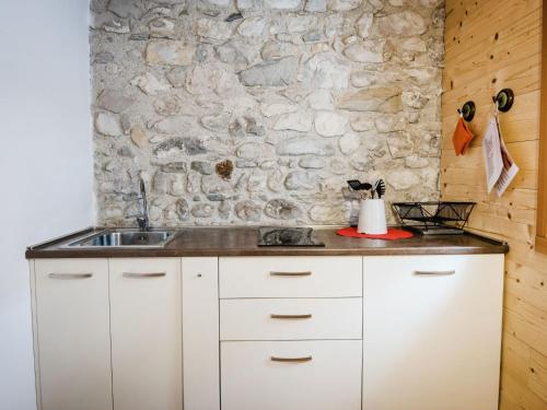 una cucina con armadi bianchi e un muro in pietra di Apartment Albergo Diffuso - Cjasa Ustin-5 by Interhome a Barcis