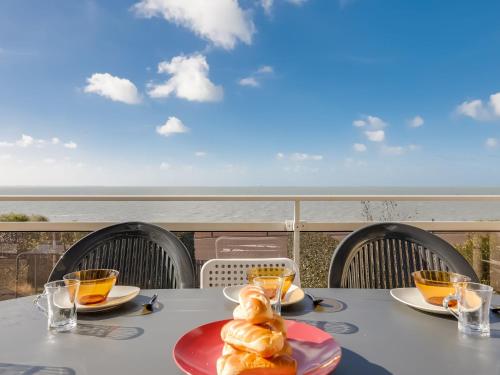 - une table avec des assiettes de nourriture et une vue sur l'océan dans l'établissement Holiday Home La Grande Côte by Interhome, à La Palud