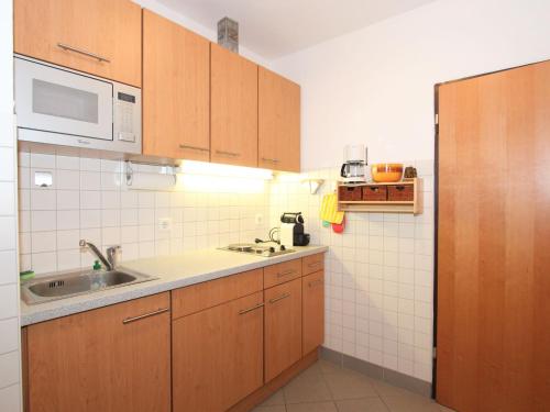una piccola cucina con armadi in legno e lavandino di Apartment Alpenland-21 by Interhome a Seefeld in Tirol