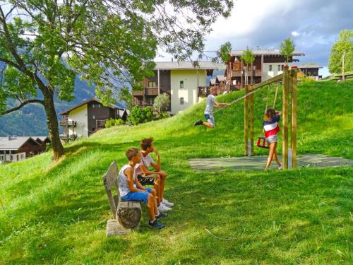 a group of children sitting on a bench in a park at Apartment Aragon M88 by Interhome in Ernen