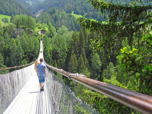 a man walking on a suspension bridge in the mountains at Apartment Aragon M88 by Interhome in Ernen