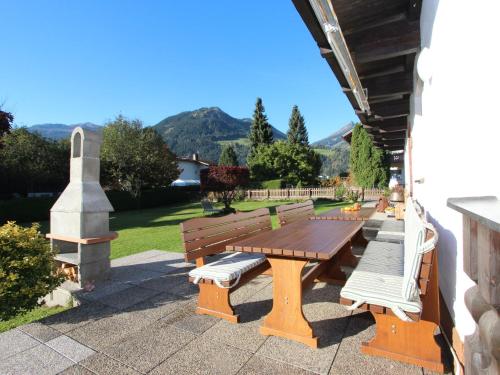 a picnic table and benches on a patio with mountains in the background at Holiday Home Sonnblick by Interhome in Uderns