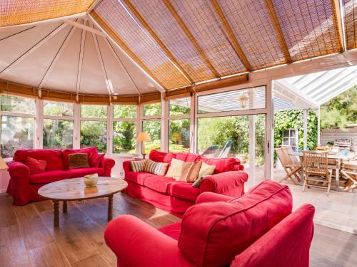 una sala de estar con muebles de color rojo en un salón acristalado en Holiday Home Villa Pieds Dans l'Eau Enez Thinic by Interhome, en Saint-Pierre-Quiberon