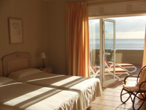 a bedroom with two beds and a balcony with the ocean at La Muralla Apartamentos in Puerto Naos