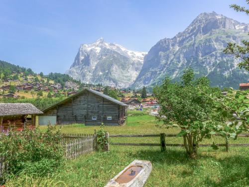 a village in a field with a mountain in the background at Apartment Chalet Chilchboden by Interhome in Grindelwald