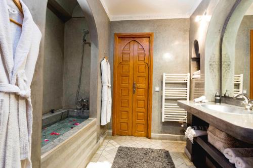 bagno con vasca e porta in legno di Riad Mazaya a Marrakech