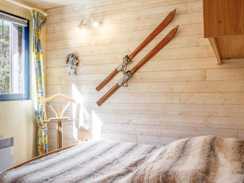 een slaapkamer met een houten wand waaraan twee ski's hangen bij Apartment Le Bochate-8 by Interhome in Saint-Pancrace