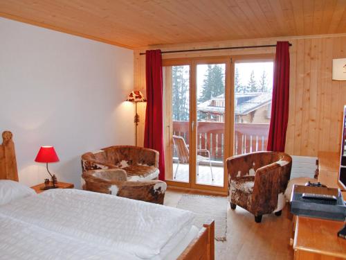 een slaapkamer met een bed en stoelen en een balkon bij Studio Montagnards 13 by Interhome in Villars-sur-Ollon
