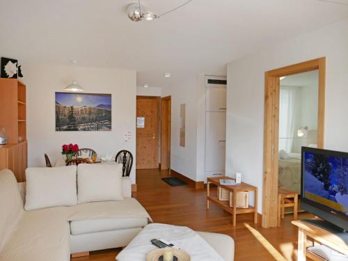 un soggiorno con divano bianco e TV di Apartment Chesa San Bastiaun B5 by Interhome a Samedan