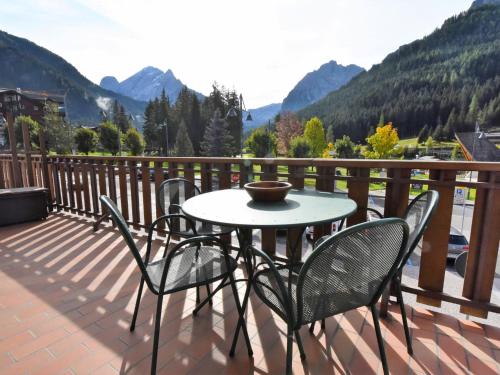 een tafel en stoelen op een balkon met uitzicht op de bergen bij Apartment Al Parco-3 by Interhome in Canazei