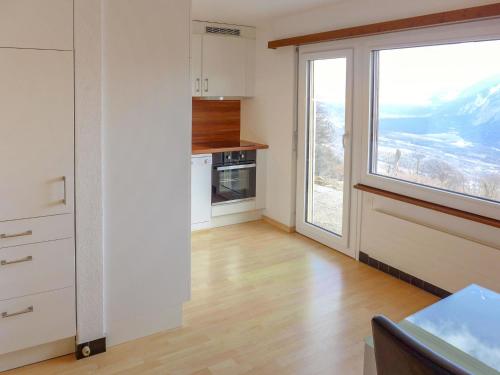 a kitchen with white cabinets and a large window at Chalet Maison Le Fontany by Interhome in Randogne