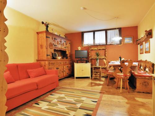 a living room with a red couch and a table at Apartment Enrosadira-3 by Interhome in Alba di Canazei