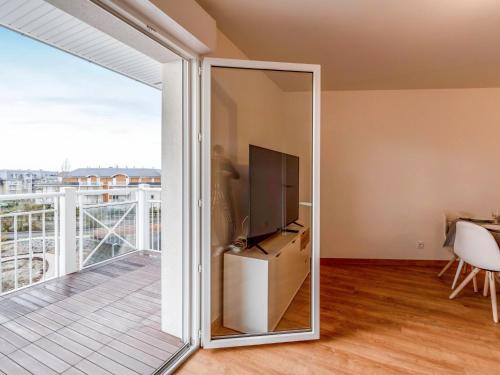 a sliding glass door leading to a balcony with a television at Apartment Les Cavaliers by Interhome in Cabourg