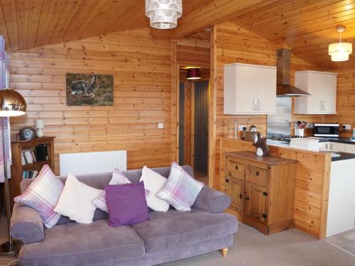 sala de estar con sofá y cocina en Chalet Osprey Lodge by Interhome, en Kinross