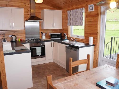 a kitchen with white cabinets and a stove at Chalet Osprey Lodge by Interhome in Kinross