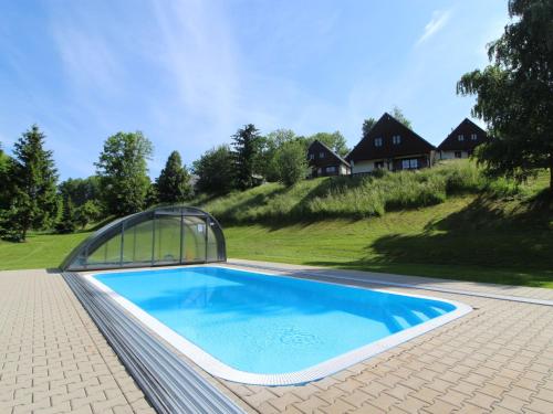 ein Pool mit einem Gewächshaus neben einem Haus in der Unterkunft Holiday Home Holiday Hill 45 by Interhome in Lauterwasser