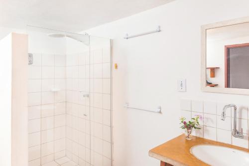 a white bathroom with a shower and a sink at Pousada Do Guga in Caraíva