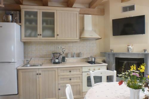 een keuken met witte kasten, een tafel en een open haard bij To Petradi in Avgonyma