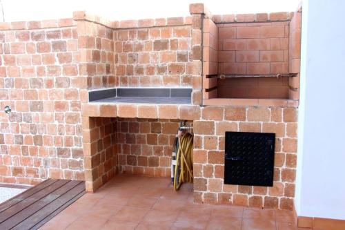 Casa Los Molinos في Villaverde: مطبخ من الطوب مع حوض ومدفأة
