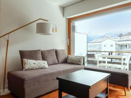 a living room with a couch and a large window at Studio Bouleaux B1 by Interhome in Nendaz