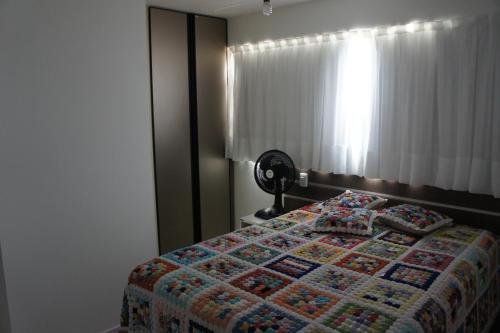 a bedroom with a bed with a quilt and a fan at Pajuçara beach - 2 QUARTOS in Maceió